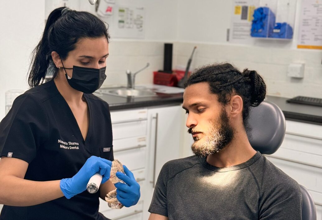 Dr Namrata Sharma speaking to a young male patient who is sat in the dentist's chair