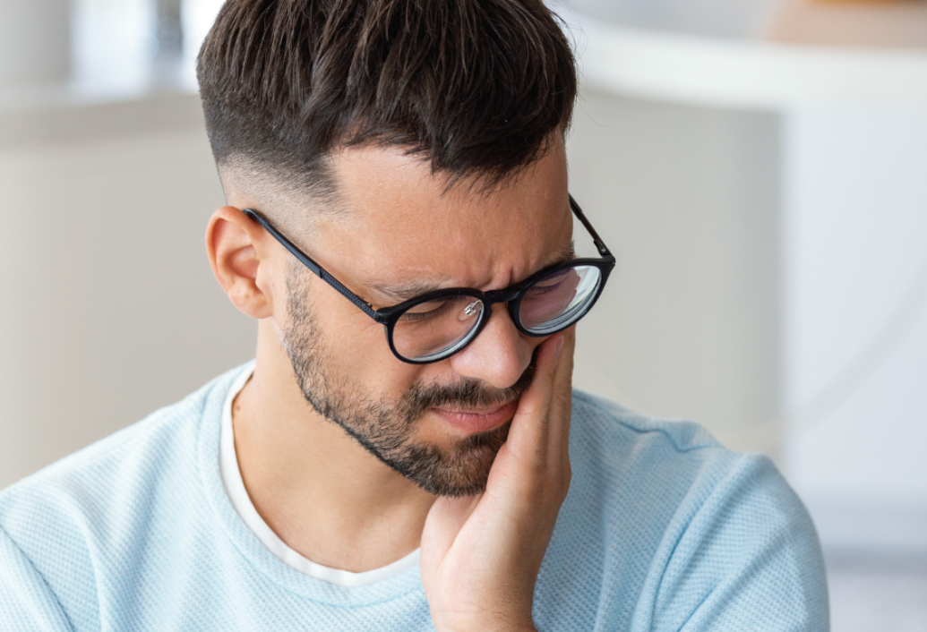 Male in his thirties holding his hand to his face due to toothache.